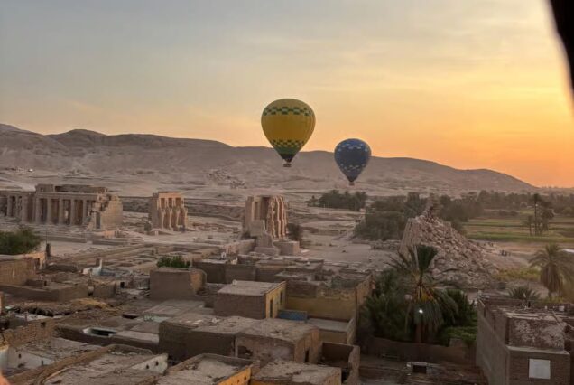 Hot air balloon over Luxor, Egypt, at sunrise with views of temples, fields, and the Nile Valley.