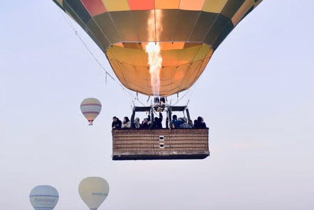 Hot air balloons rising over Luxor, Egypt at sunrise, overlooking the Nile River and the Valley of the Kings.