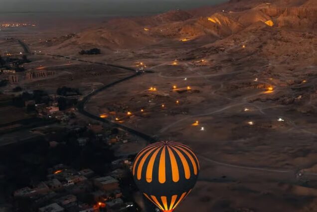 Hot air balloons over Luxor, Egypt at sunrise, with views of the Nile River, fertile fields, desert, and ancient monuments.