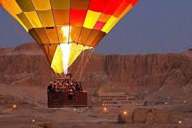 "Hot air balloon flying over Luxor, Egypt at sunrise, with views of the Nile River and ancient temples on the West Bank."