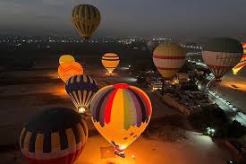 "Hot air balloons ascending at sunrise over Luxor, Egypt, with views of the Nile and ancient temples."