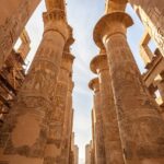 Interior view of the Great Hypostyle Hall at Karnak Temple, showing rows of towering columns covered in hieroglyphics and reliefs.