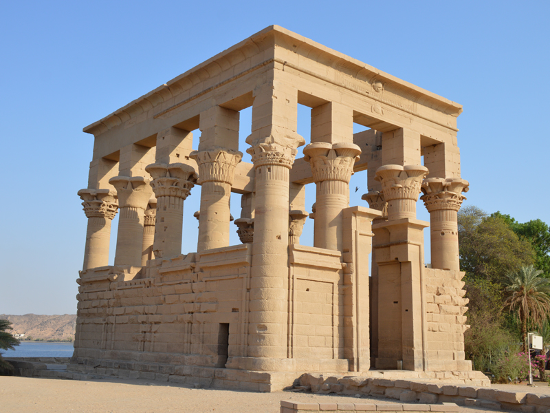 The Kiosk of Trajan, part of the Philae Temple complex in Aswan, Egypt, is a remarkable example of Roman architecture in an ancient Egyptian sacred setting. Built during the reign of Emperor Trajan, the structure once featured a roof that has since disappeared, leaving behind its elegant open-air design supported by ornate columns. Originally located on Philae Island, the entire temple complex — including the Kiosk — was relocated to Agilkia Island between 1970 and 1980 by UNESCO to protect it from submersion caused by the creation of Lake Nasser after the Aswan High Dam’s construction. Dedicated to the goddess Isis, the Philae Temple complex was a major center of worship and pilgrimage in ancient Egypt. Today, the Kiosk of Trajan remains a symbol of both Egypt’s rich history and the global effort to preserve it.