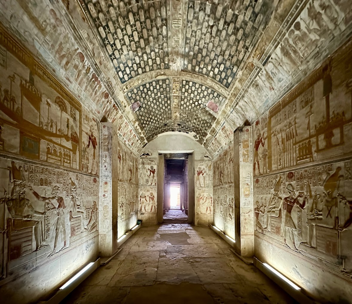 Interior of an ancient Egyptian temple with vivid reliefs and hieroglyphs, possibly Abydos or the Valley of the Kings.