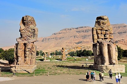 Two colossal stone statues of Pharaoh Amenhotep III seated on the west bank of the Nile near Luxor, Egypt.