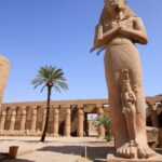 Stone statues of Pharaoh Ramesses II and his wife, standing side by side in Karnak Temple, Luxor, Egypt.
