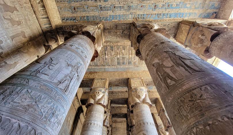Interior of the Temple of Hathor at the Dendera Temple Complex in Egypt, showcasing Hathor-headed columns and detailed astronomical ceiling engravings.