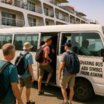 Travelers with backpacks board a white shuttle bus labeled “SHARING BUS ABU SIMBEL FROM ASWAN” for a shared group tour in Egypt.