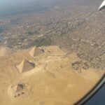 Aerial view of the Giza Necropolis showing the three Great Pyramids from an airplane window.