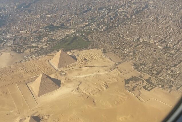 Aerial view of the Giza Necropolis showing the three Great Pyramids from an airplane window.