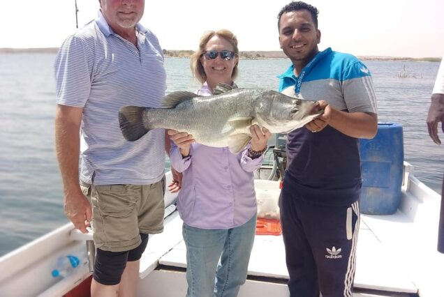 Group of anglers proudly displaying a large Nile Perch caught during a fishing trip on Lake Nasser, Egypt.