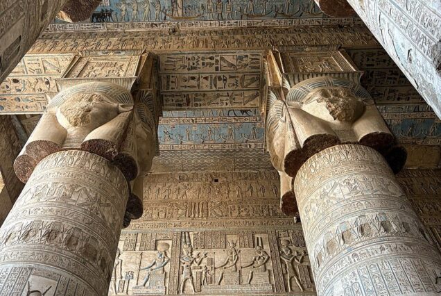 The Great Hypostyle Hall of the Temple of Hathor at Dendera, featuring massive columns topped with Hathor-headed capitals and decorated with intricate reliefs.
