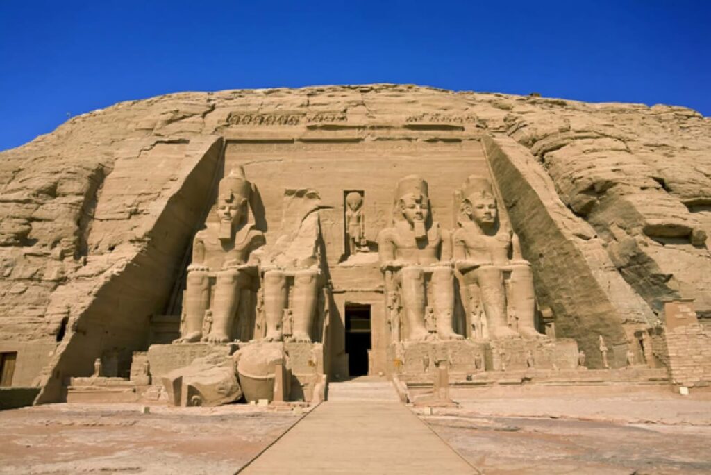 Great Temple of Abu Simbel in southern Egypt, with four colossal seated statues of Ramesses II carved into a sandstone cliff.