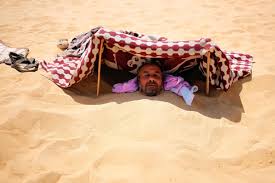 A person undergoing a traditional Siwa sand bath, buried in hot desert sand for therapeutic healing.