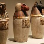 Ancient Egyptian Canopic Jars with lids representing the Four Sons of Horus, used to store and protect organs during mummification.