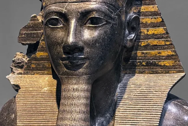 Upper part of a statue of King Thutmose III wearing the royal Nemes headdress and Uraeus, symbolizing kingship in ancient Egypt.