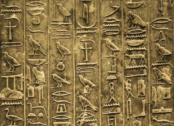 "Ancient Egyptian hieroglyphs carved into stone, showing pictorial symbols used for writing sacred and official texts."